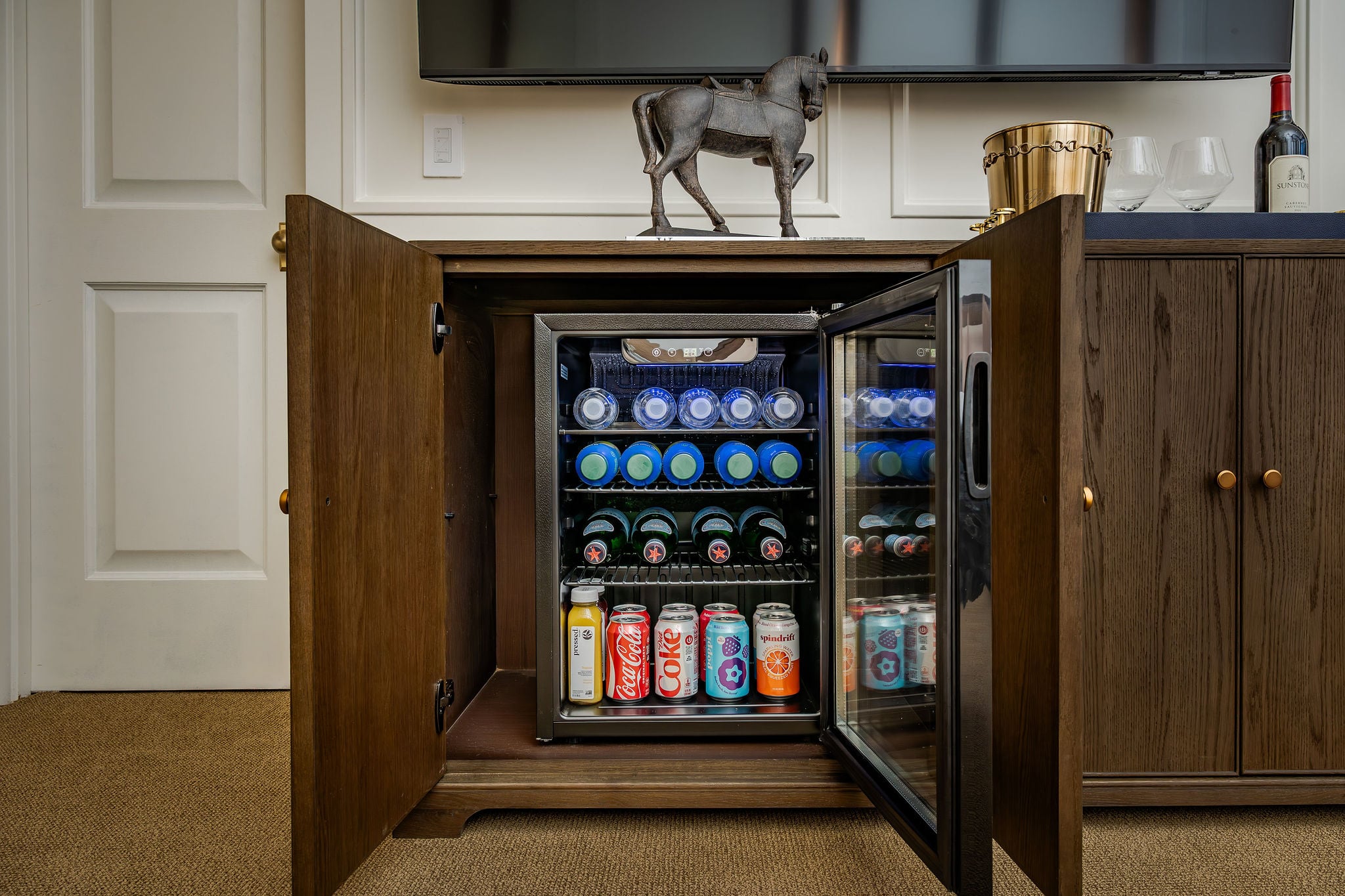 An in-room oak cabinet with a stocked beverage fridge at The Polo House