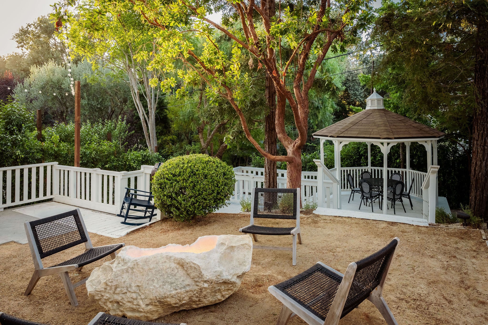The stone fire pit with lounge chairs beside the garden gazebo at The Polo House