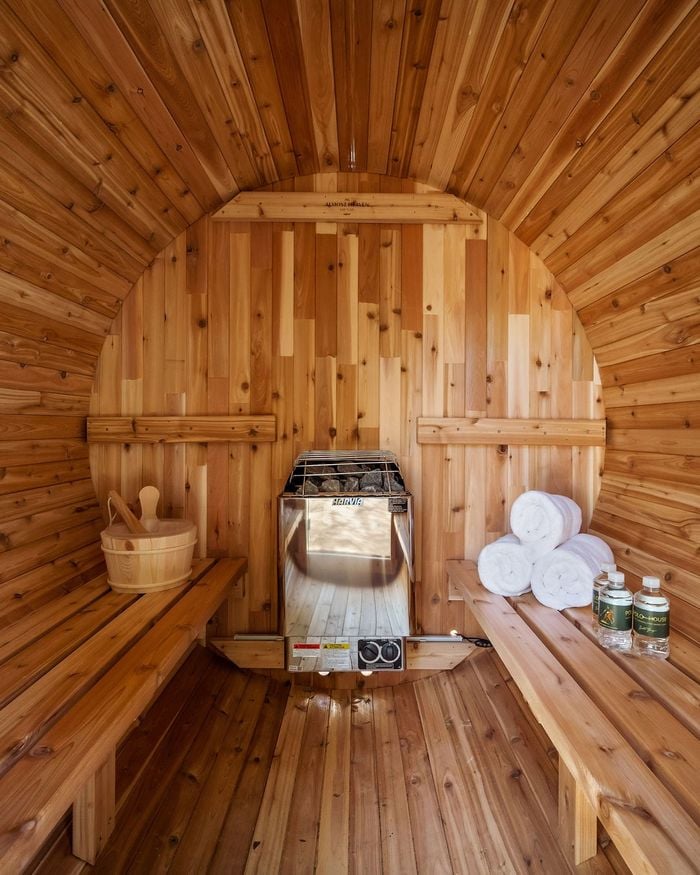 Inside the cedar barrel sauna, with rolled towels and Polo House water on the bench